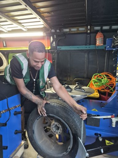 Mobile tire install in Secaucus NJ — technician fitting a new tire on a sedan in a parking lot