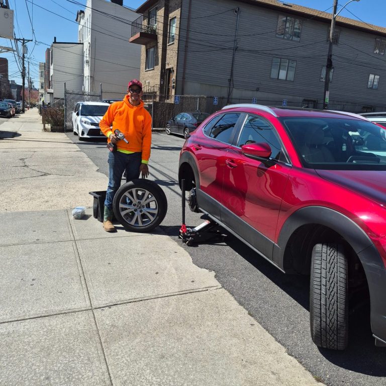 Happy Road Services technician changing a flat tire for a driver in Hoboken NJ — 24/7 roadside tire service