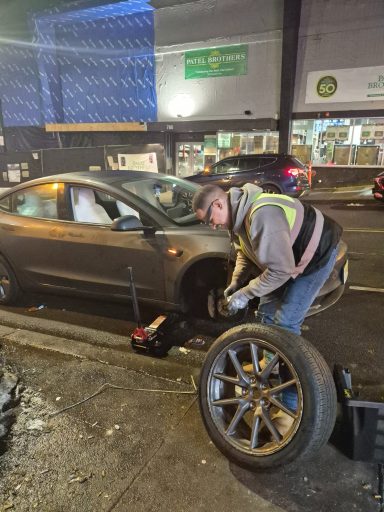 Happy road services Roadside assistance in jersey city NJ fixing flat tire and helping Tesla driver
