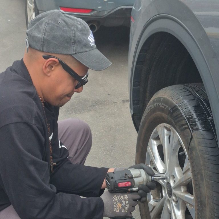 Happy Road Services changing a flat tire on a Ford in Bayonne NJ — mobile tire repair and roadside assistance