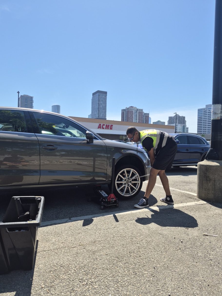 Flat Tire Change in Jersey City, NJ | Happy Road Services Roadside technician changing a flat tire on an Audi sedan in a Jersey City NJ parking lot