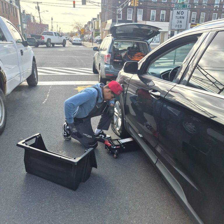 Happy Road Services technician performing flat tire change and roadside tire repair in Bayonne NJ